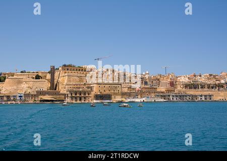 Valletta, Malta - 17. Juni 2023: Golf zwischen Valletta und Vittoriosa mit vorbeifahrenden Booten und typischen Luzzu und Valletta im Hintergrund Stockfoto