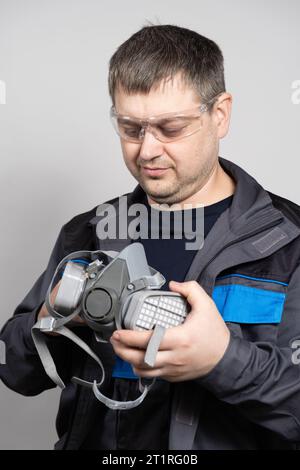 Ein Mann hält eine Atemschutzmaske zum Schutz vor Staub und Gasen. Stockfoto