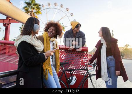 Gruppe junger, multiethnischer, fröhlicher Menschen, die kalte, sonnige Wintertage treffen, chatten und telefonieren. Stockfoto