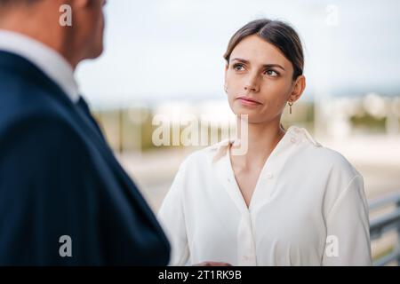Eine Frau, die ein gelbes Kleid trägt, hat ihren Arm um den Hals eines Mannes, der ein weißes T-Shirt und eine blaue Jeans trägt Stockfoto