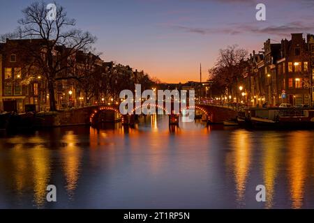 Landschaftlich reizvolle Stadt von Amsterdam am Fluss Amstel in den Niederlanden bei Sonnenuntergang Stockfoto