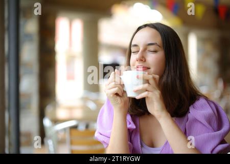 Eine entspannte Frau riecht Kaffee auf einer Restaurantterrasse Stockfoto