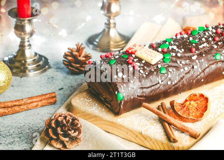 Traditioneller Weihnachtskuchen. Schoko Yule mit weihnachtsdekoration auf einem Holzbrett. Dessertkonzept für Weihnachten Stockfoto