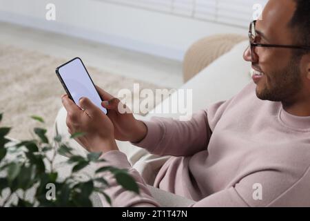 Mann, der zu Hause ein modernes Mobiltelefon benutzt, selektiver Fokus Stockfoto