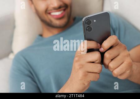 Mann sendet Nachrichten über Smartphone in Innenräumen, selektiver Fokus Stockfoto