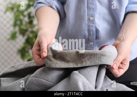 Frau zeigt Flecken vom Kaffee auf der Jacke vor verschwommenem Hintergrund, Nahaufnahme Stockfoto