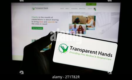 Person, die ein Smartphone mit transparenten Händen des Logos der US-amerikanischen gemeinnützigen Organisation vor der Website hält. Schwerpunkt auf dem Display des Telefons. Stockfoto