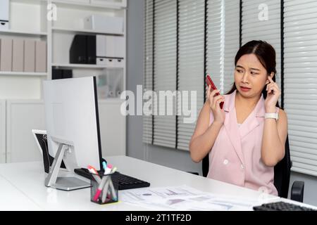 Wütende asiatische Geschäftsfrau, die geschrien, beschimpft wurde und sich auf dem Handy beschwerte, weil sie sich im Bürozimmer beschwerte. - Business Fight and Conflict at Workplace Konzept Stockfoto