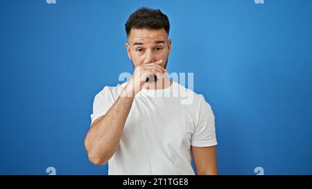 Junger araber, der krank ist und über isolierten blauen Hintergrund hustet Stockfoto