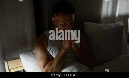 Junger arabischer Mann, der auf dem Bett sitzt und im Schlafzimmer betet Stockfoto