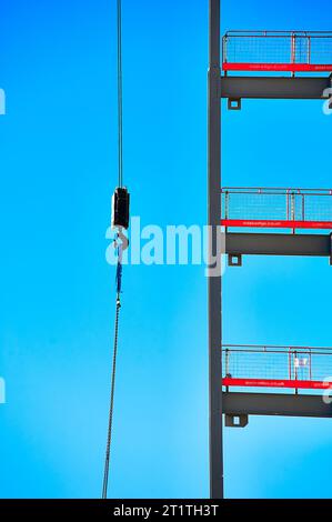 Kranhaken und Skelett des im Bau befindlichen Gebäudes vor blauem Himmel Stockfoto