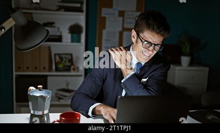 Junger hispanischer Geschäftsmann, der unter Rückenschmerzen leidet und im Büro arbeitet Stockfoto