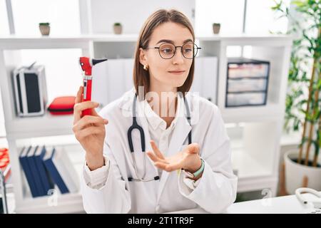 Junge Kaukasierin, die Otoskop in der Klinik hält Stockfoto