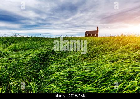 Lonely Budakirkja christliche Kirche sitzt unter einem Feld von Lavagestein. Dramatische Szene. Beliebte Touristenattraktion. Ort Weiler Budir, Snafel Stockfoto