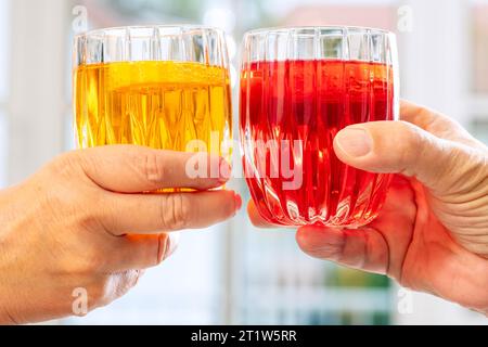 Zuprosten mit Crodino und Martini Vibrante, beides alkoholfreie italienische Aperitifs, Symbolfoto Trend alkoholfrei, München, Oktober 2023 Deutschland, München, Oktober 2023, anstoßen mit Crodino und Martini Vibrante, beide alkoholfreie italienische Aperitifs, Crodino gehört zu Davide Campari-Milano und wird in Crodo hergestellt, Martini ohne Alkohol rechts italienischer Aperitif, Hersteller Martini & Rossi S.P.A. in Turin, eiskalt serviert, Paar stoßen mit Gläsern an, bunte Schirmchen als Deko, Symbolfoto zu Trend alkoholfrei, Jugendliche trinken immer weniger Alkohol, Alkoholkonsum sinkt, es Stockfoto