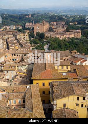 Die Basilika des Heiligen Franziskus über den Dächern von Siena mit der Landschaft im Hintergrund, von der Spitze des Torre del Mangia aus gesehen Stockfoto