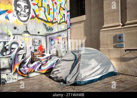 Paris, Frankreich - 21. Februar 2023: Soziale Gegensätze. Zelt des Obdachlosen, Graffiti der Wohnung und Platte des historischen Denkmals (gehört zu einer Kirche) Stockfoto