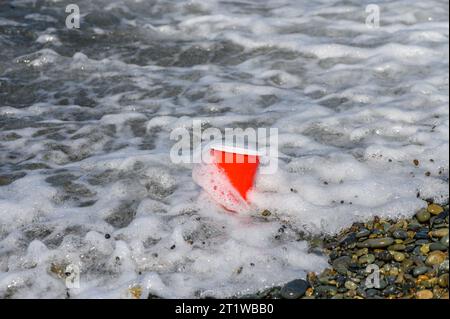 Rotes Plastikglas mit Müll, das am Mittelmeerstrand angespült wurde. 4 Stockfoto