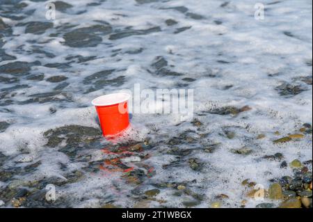 Rotes Plastikglas mit Müll wurde am Mittelmeerstrand angewaschen. 3 Stockfoto