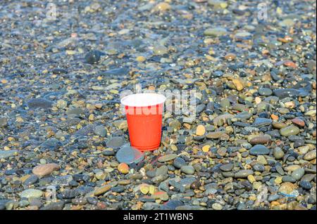 Rotes Plastikglas mit Müll wurde am Mittelmeer-Strand aufgewaschen. 2 Stockfoto