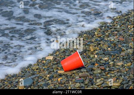 Rotes Plastikglas mit Müll wurde am Mittelmeerstrand aufgewaschen 1 Stockfoto