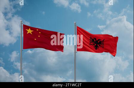 China- und Albanienflaggen winken zusammen im Wind auf blauem bewölktem Himmel Stockfoto