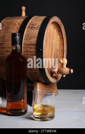 Fass mit Wasserhahn, Flasche und Glas leckeren Whiskey auf hellgrauem Holztisch Stockfoto