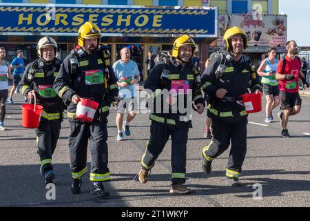 Great South Run, 15. Oktober 2023, Portsmouth, Hampshire, England, UK. Tausende von Teilnehmern liefen im 16-Mile-Great South Run in Southsea, Portsmouth. Neben den Elite-Läufern nahmen auch viele andere Teilnehmer Teil, die für Wohltätigkeitsorganisationen oder ihre Vereine gelaufen waren. Im Bild: Feuerwehrmänner laufen, um Geld für die Feuerwehrorganisation zu sammeln Stockfoto