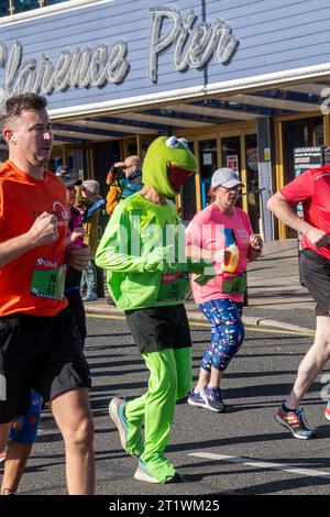 Great South Run, 15. Oktober 2023, Portsmouth, Hampshire, England, UK. Tausende von Teilnehmern liefen im 16-Mile-Great South Run in Southsea, Portsmouth. Neben den Elite-Läufern nahmen auch viele andere Teilnehmer Teil, die für Wohltätigkeitsorganisationen oder ihre Vereine gelaufen waren. Ein Läufer, verkleidet als Kermit der Frosch, der an Clarence Pier vorbeifährt Stockfoto