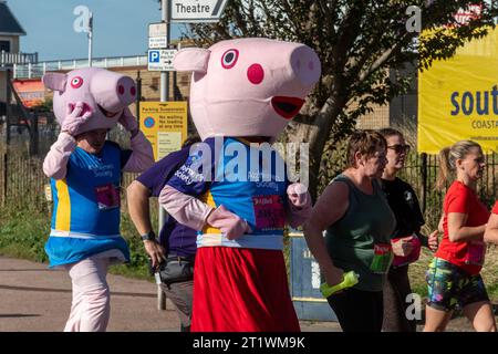 Great South Run, 15. Oktober 2023, Portsmouth, Hampshire, England, UK. Tausende von Teilnehmern liefen im 16-Mile-Great South Run in Southsea, Portsmouth. Neben den Elite-Läufern nahmen auch viele andere Teilnehmer Teil, die für Wohltätigkeitsorganisationen oder ihre Vereine gelaufen waren. Im Bild: Zwei Läufer in Peppa-Schweinekostümen, die Geld für die Alzheimers Society-Wohltätigkeitsorganisation sammeln Stockfoto