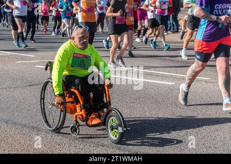 Great South Run, 15. Oktober 2023, Portsmouth, Hampshire, England, UK. Tausende von Teilnehmern liefen im 16-Mile-Great South Run in Southsea, Portsmouth. Neben den Elite-Läufern nahmen auch viele andere Teilnehmer Teil, die für Wohltätigkeitsorganisationen oder ihre Vereine gelaufen waren. Im Bild: Ein Rollstuhlfahrer, der neben vielen Läufern an der Veranstaltung teilnimmt Stockfoto