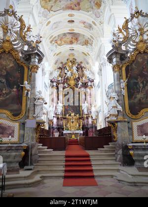 Blick auf den Chor mit rotem Teppich und Hochaltar mit großem Bild in der barocken Klosterkirche Schöntal Stockfoto