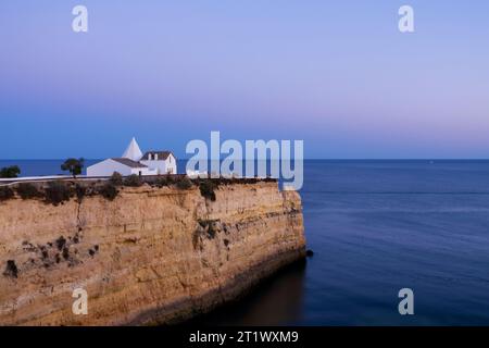 Blick auf die große Klippe und die Kapelle unserer Lieben Frau vom Felsen (Igreja de Nossa Senhora da Rocha). Traumhafte, ruhige Landschaft bei Sonnenuntergang. Veranden, Algarve, Po Stockfoto