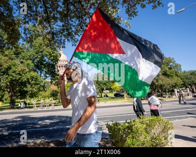 Austin, Texas, USA. 15. Oktober 2023: Ein Mann mit palästinensischer Flagge und Keffiyeh läuft am 15. Oktober 2023 am Texas Capitol vorbei, als 250 Menschen während eines pro-palästinensischen marsches zum Texas Capitol in Austin zusammentreten. Das Texas Department of Public Safety (DPS) behielt die Veranstaltung aufmerksam im Auge, während es einige israelisch-palästinensische Geschrei-Spiele bei der meist friedlichen Veranstaltung trennte. ©Bob Daemmrich Stockfoto