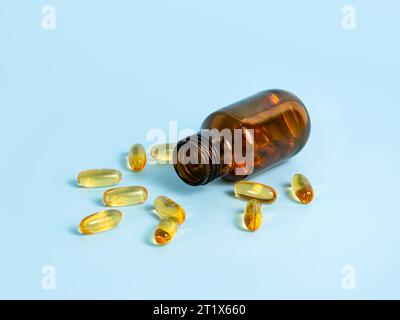 Omega-3-Kapseln in der Nähe der geöffneten Flasche auf blauem Hintergrund. Fischöl-Vitamine und Nahrungsergänzungsmittel in der Therapie oder wissenschaftlichen Forschung. Nahaufnahme, selektiver Fokus Stockfoto