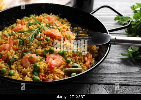 Leckerer Reis mit Garnelen und Gemüse in der Pfanne auf grauem Holztisch, Nahaufnahme Stockfoto