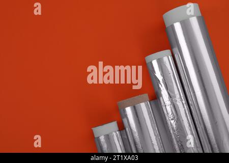 Rollen aus Aluminiumfolie auf rotem Hintergrund, flache Lagen. Leerzeichen für Text Stockfoto