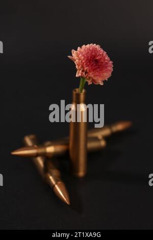 Kugeln und Patronenkoffer mit schöner Blume auf schwarzem Hintergrund Stockfoto