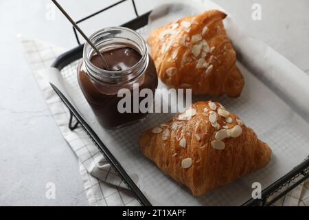 Köstliche Croissants mit Mandelflocken und Schokoladenpaste auf hellgrauem Tisch, Nahaufnahme Stockfoto