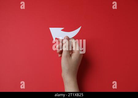 Frau mit einem gebogenen Papierpfeil auf rotem Hintergrund, Draufsicht Stockfoto