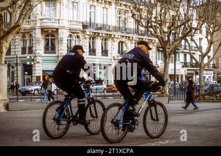 Französische Polizeibeamte radeln über einen Stadtplatz in Beziers, Herault, in der Region Occitanie in Südfrankreich Stockfoto