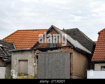 Alte Gebäuderuine mit Tür und Fenster. Das Äußere ist verwittert und in sehr schlechtem Zustand. Das verlassene Haus steht in einer Stadt. Stockfoto
