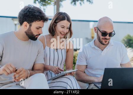 Selbstbewusste Fachleute arbeiten am Sonnentag im Freien zusammen, diskutieren über Strategie und analysieren Statistiken Stockfoto