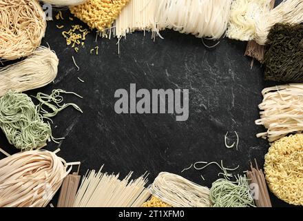 Verschiedene Arten Rohe Asiatische Nudeln, Soba, Ramen, Ramyeon, Misua, Char Kway Teow, Gemüseeiernudel, Etwas. Auf Tisch aus schwarzem Marmor mit Kopierraum auf dem Stockfoto