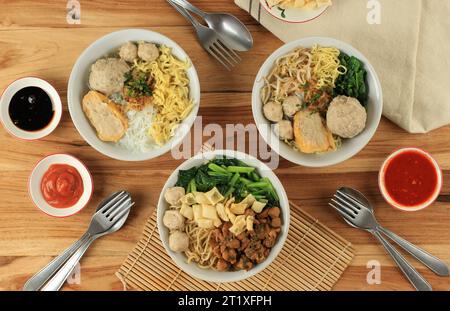 Mie Baso oder Bakso, Fleischbällchensuppe mit Nudeln, Gemüse und Reisnudeln. Blick von oben auf Holztisch Stockfoto
