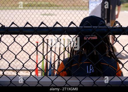 Kleiner Baseballspieler, der im Dugout sitzt. Stockfoto