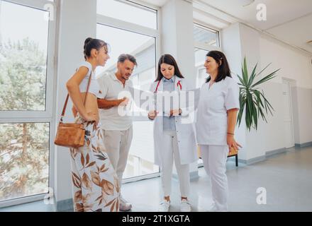Fachärzte beraten ein glückliches Paar in einem Büro. Diagnose, Behandlung und Lösungsfindung für gesundheitliche Probleme. Stockfoto