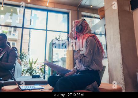 Seitenaufnahme einer Mitarbeiterin in Hijab, die ihren Projektmanager konsultierte und Informationen, Daten und Berichte besprich Stockfoto