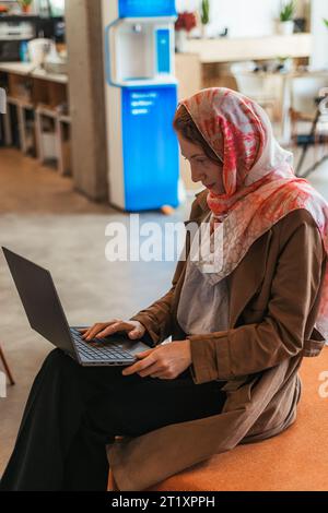 Geschäftsfrau im Hijab, die auf dem Laptop arbeitet. Seitenansicht Foto Stockfoto