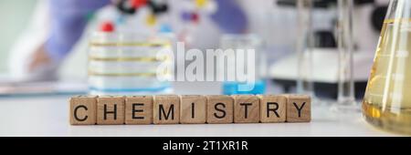 Word Chemistry aus Würfeln in der Nähe von Laborglasgeräten Stockfoto